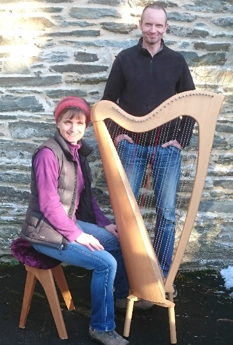 Sarah seated by harp and Gareth standing